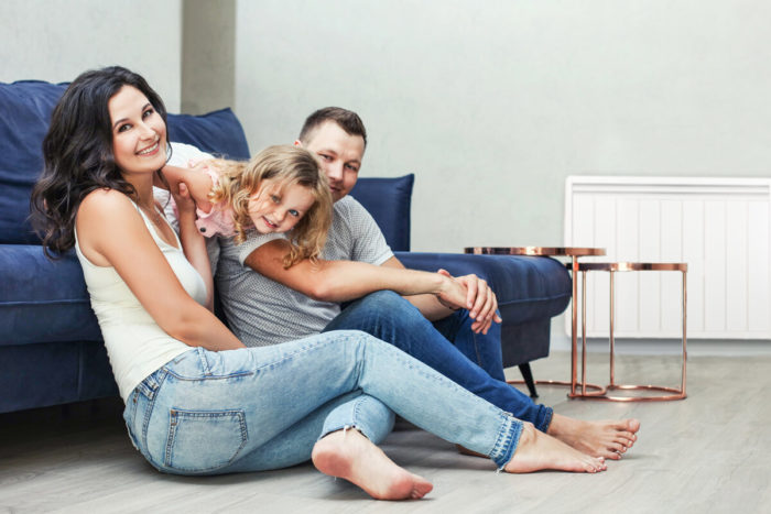 Famille dans son salon avec un chauffage electrique Aterno. Une bonne alternative au remplacement de  votre chaudiere au fioul.